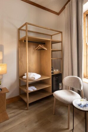 Una habitación con una cama litera de madera, una silla, una mesita y una lámpara.