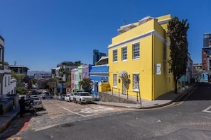 Una calle con edificios coloridos, un automóvil estacionado y un cielo azul despejado.