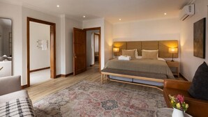 Ett hotellrum med en stor säng, ett sängbord, en stol, en soffa och en matta.
