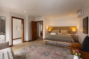 Una habitación de hotel con una cama grande, una mesita de noche, una silla, un sofá y una alfombra.