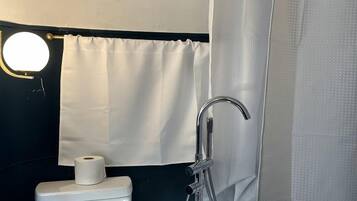 Un bagno con il water, una doccia e una tenda.
