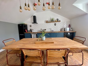 Eine moderne Küche mit einem Holztisch, Metallstühlen und Pendelleuchten.