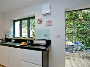 Eine moderne Küche mit eingebautem Herd, Spüle und Fenster mit Blick auf einen Garten.