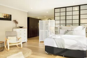 A modern bedroom with a bed, a desk, and a wardrobe. - Seabatical Retreat minutes from the beach (Auckland)