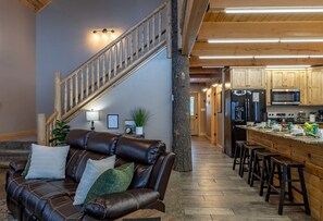 Ein modernes Interieur mit einer Ledersofa, einer Holztreppe und einer Küche mit Barhocker.