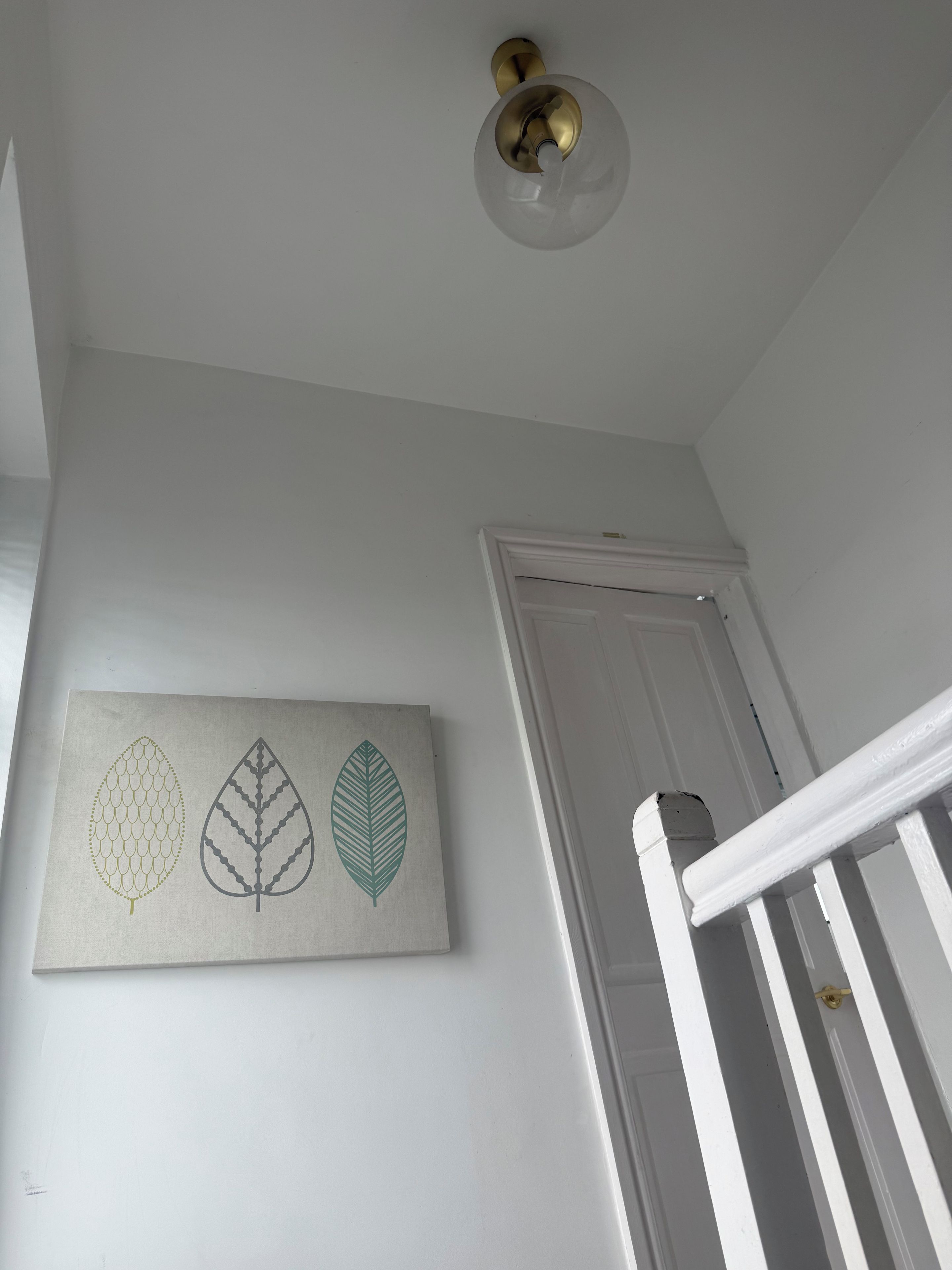 A white wall with a door and a staircase.