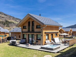 Un chalet en bois doté d’une terrasse, de meubles de jardin et d’un bain à remous.