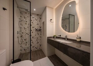Ein modernes Badezimmer mit einer Duschkabine aus Glas, einem großen Spiegel und einer Marmorarbeitsplatte.