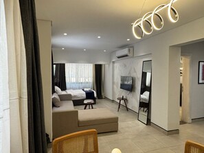 Ein modernes Wohnzimmer mit einer Couch, einem Hocker und einem an der Wand befestigten Fernseher.