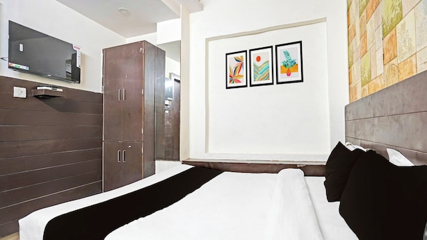 Quarto de hotel com cama, guarda-roupa e televisão na parede.