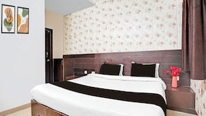 Quarto com cama, mesa de cabeceira, um vaso de flores e uma porta.