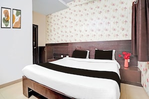 Un dormitorio con cama, mesita de noche, un florero y una puerta.
