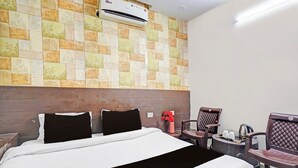 Quarto de hotel com cama, cadeira, mesa pequena e ar condicionado na parede.