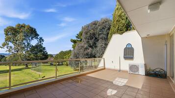 A balcony with a view of a grassy area and trees.
