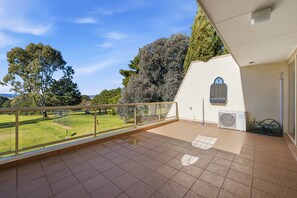 A balcony with a view of a grassy area and trees. - Spacious 2-bedroom Retreat With Golf Course Views (Canberra)