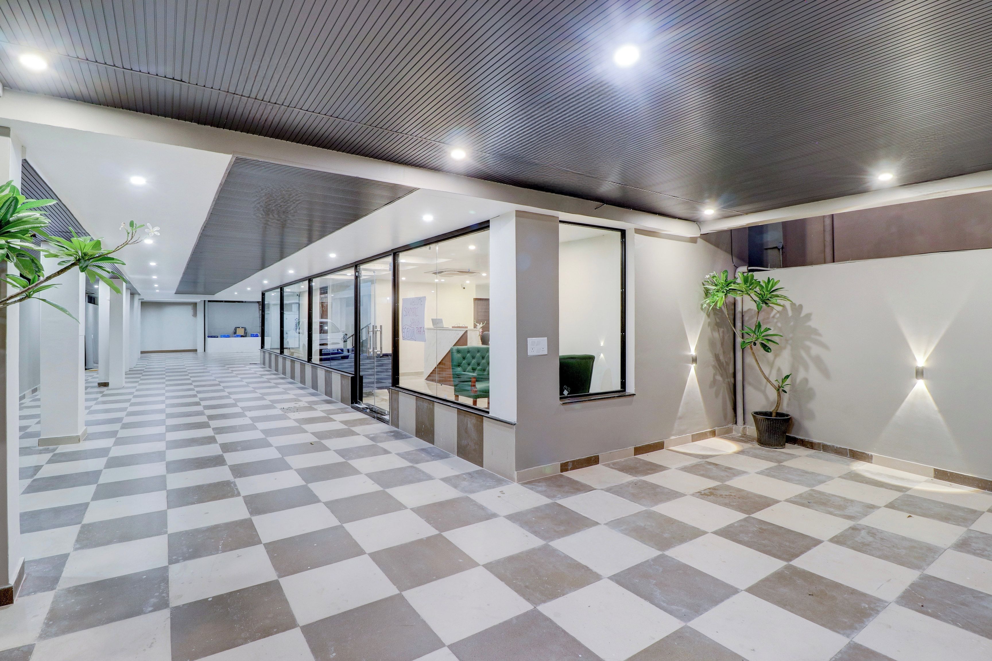 Um interior moderno com piso xadrez, divisórias de vidro e plantas em vasos.