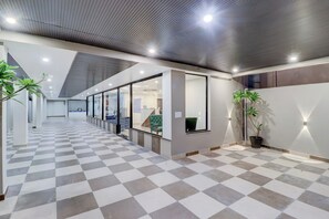 Un interior moderno con piso a cuadros, divisiones de vidrio y plantas en macetas.