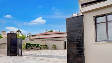 A gated entrance with a paved driveway leading to a building with a red roof.