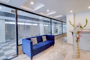 Un intérieur moderne avec un canapé bleu, un vase de fleurs et un sol à carreaux.