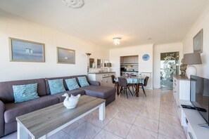 A living room with a sofa, coffee table, and a dining area with chairs and a table. - Apartment in Blankenberge by the North Sea (Blankenberge)