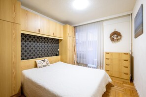 A bedroom with a bed, wooden wardrobe, and a decorative wall hanging. - Apartment in Blankenberge by the North Sea (Blankenberge)