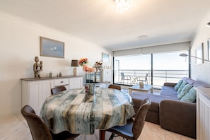 A dining area with a table, chairs, and a view of the balcony. - Apartment in Blankenberge by the North Sea (Blankenberge)