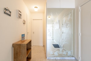 A hallway with a wooden bench, a welcome sign, a glass door with decorative elements, and a ceiling light. - Apartment in Blankenberge by the North Sea (Blankenberge)