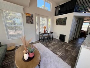 A spacious living area with a high ceiling, a dining table with chairs, and a staircase leading to an upper level. - Scenic Mountain Glampground with Dark Sky Stargazing Near Forest Trails in Fruitland, Utah (Fruitland)