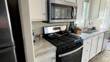 Une cuisine avec des meubles blancs, une cuisinière noire et un four à micro-ondes.