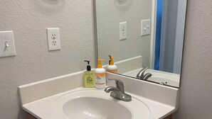 Un baño con un lavamanos blanco, un espejo, un perchero para toallas y un inodoro.