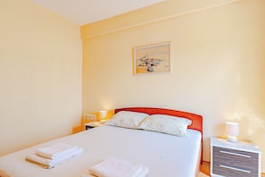 A neatly made bed with folded towels, a painting on the wall, and a bedside lamp. - A2 - Apartment 50m from the beach with the sea view (Korcula)