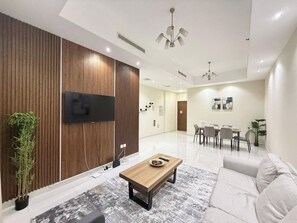 Un salon moderne doté d’un téléviseur à écran plat, d’un mur décoratif en bois, d’un coin repas avec des chaises et d’un canapé.