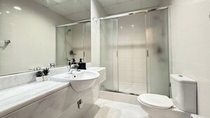 Et stilfuldt badeværelse med et stort spejl, to håndvaske, en bruseniche og et toilet.