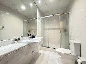 A modern bathroom with a large mirror, two sinks, a shower enclosure, and a toilet. - Sahab - Pearl Tower 1BHK 5 min From Alkhan Beach (Sharjah)
