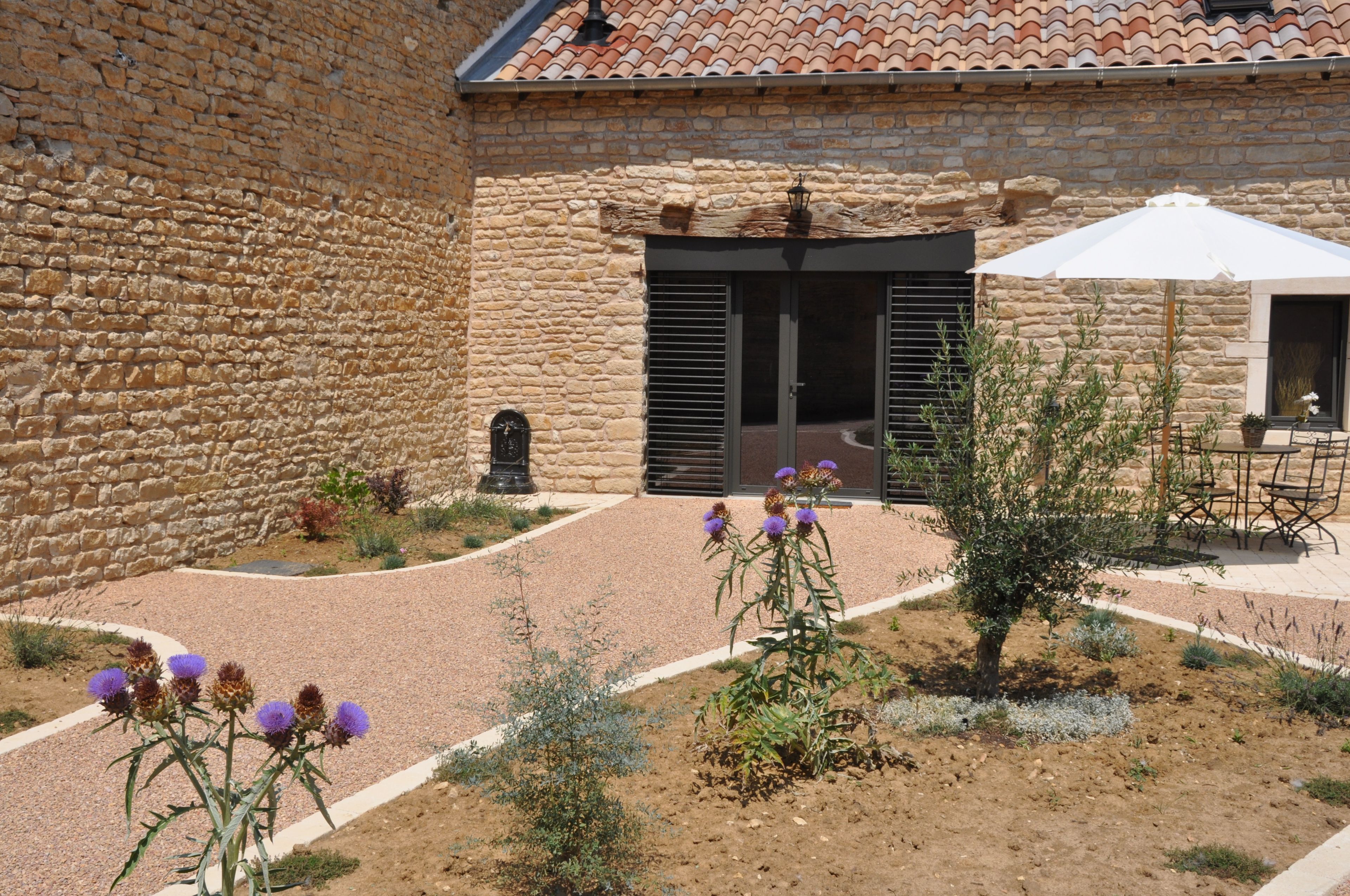 A courtyard with stone walls, a tiled roof, and outdoor seating.