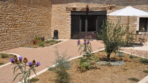 Un patio con paredes de piedra, techo de tejas y mobiliario exterior.