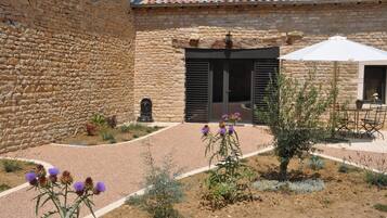 A courtyard with stone walls, a tiled roof, and outdoor seating.