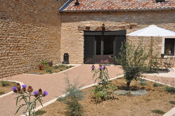 A courtyard with stone walls, a tiled roof, and outdoor seating.
