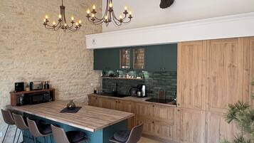 Una cucina con isola centrale, sgabelli da bar, un lampadario e una testa di animale appesa al muro.