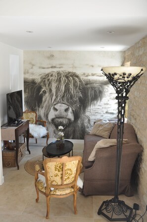 A living room with a large animal mural, a sofa, a chair, a floor lamp, and a television.