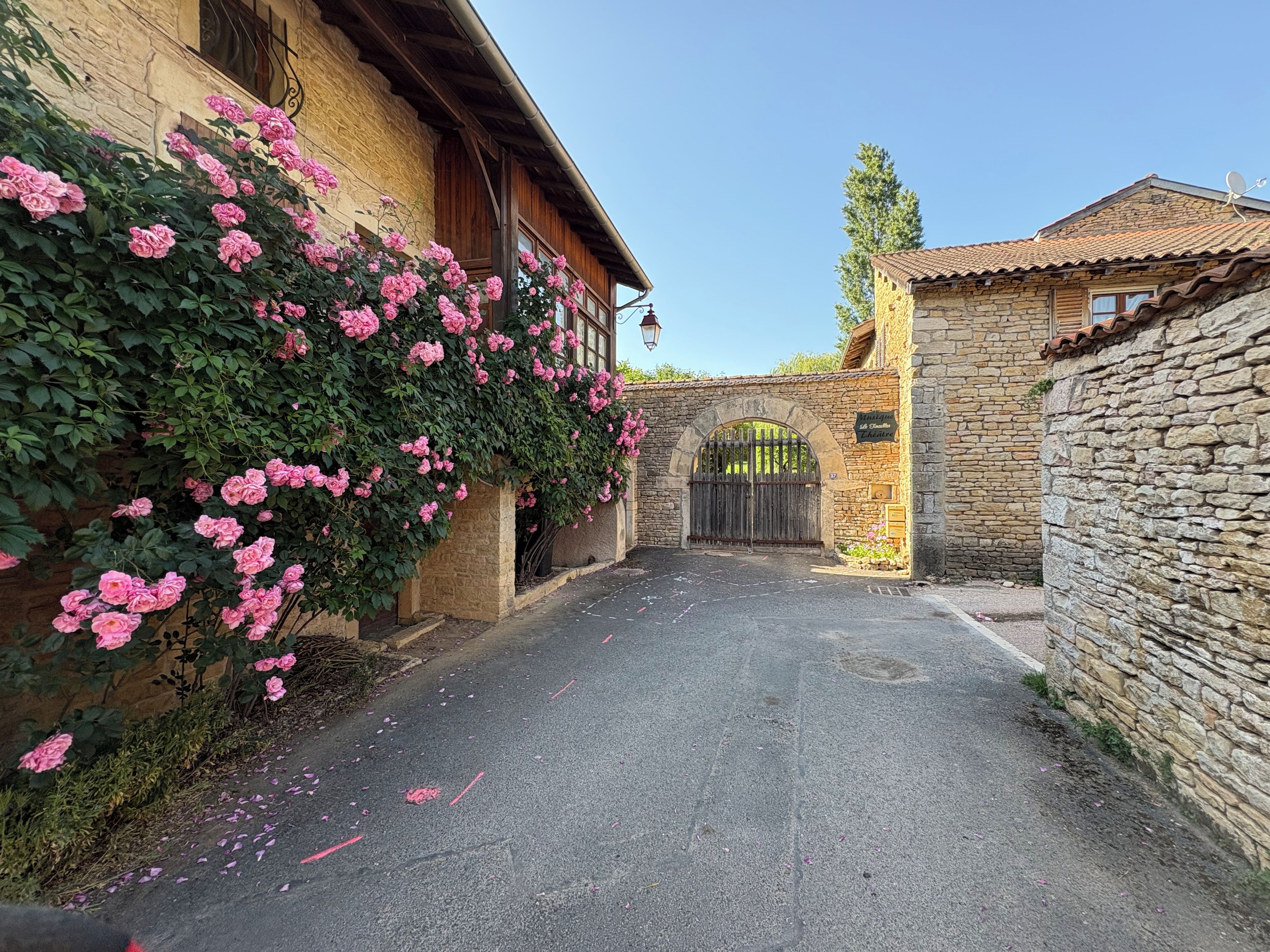 Un stretto vicolo con un muro di pietra da un lato e un edificio con una porta in legno dall'altro.
