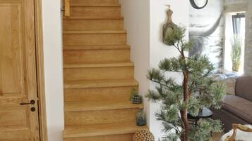 A wooden staircase leading to a living area with a pine tree, a clock, and a door.