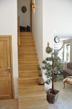 A wooden staircase leading to a living area with a pine tree, a clock, and a door.