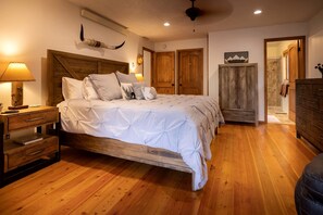 Un dormitorio con una cama de madera, mesitas de noche, un armario y un ventilador de techo.