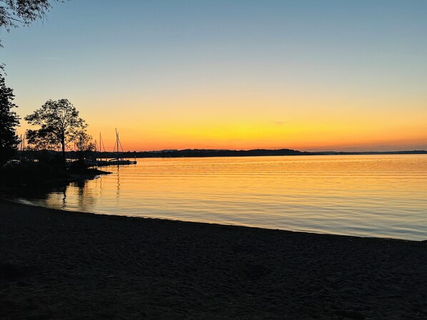 A sunset over a calm body of water with a dock and boats. - Newly renovated Berggold Chalet with the Chiemgau Card in the heart of Chiemgau (Siegsdorf)