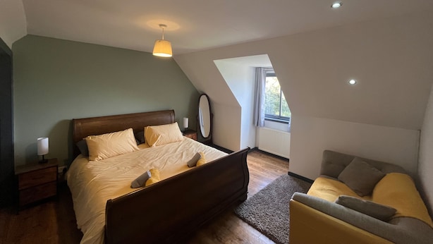 Un dormitorio con cama, mesita de noche, lámpara y ventana.