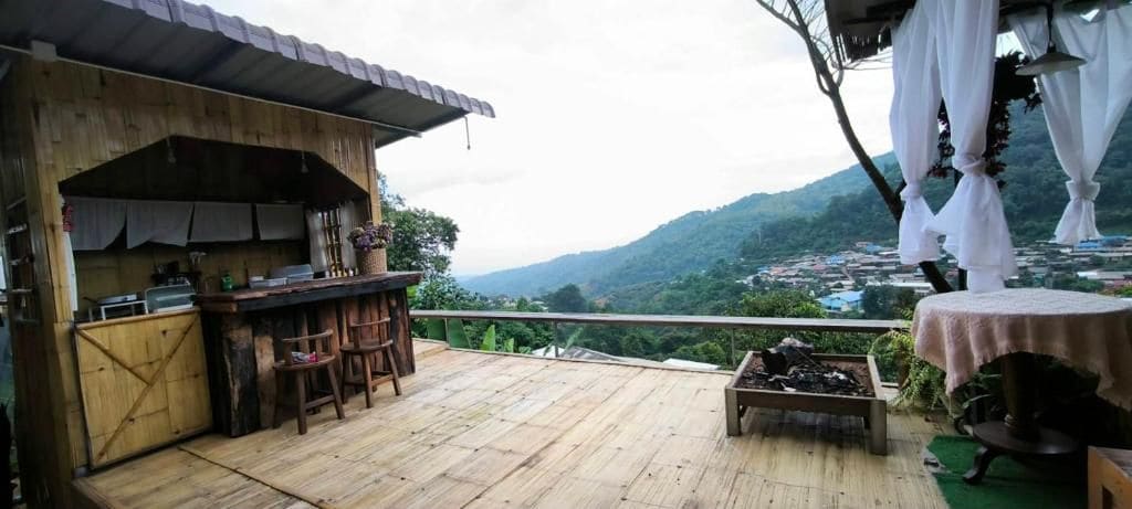 A wooden deck with a bar area and a table, overlooking a mountainous landscape.