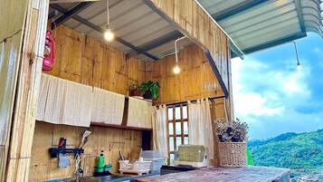 A rustic kitchen with wooden walls, a window, and a view of a green landscape.