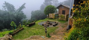 A rustic outdoor area with a wooden bench, a small wooden structure, and a garden with various plants.