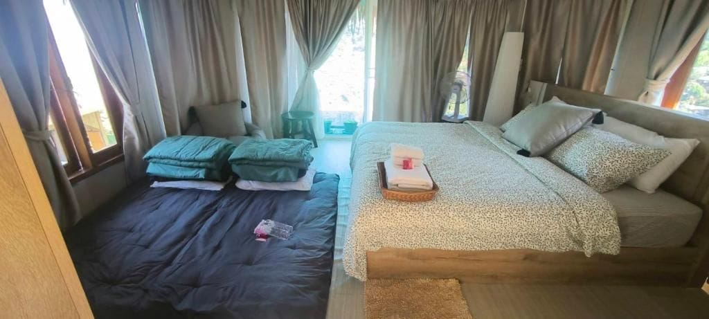A room with a bed, a smaller bed, and a window with curtains.